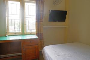 a bedroom with a bed and a desk and a television at OYO Life 92632 Kost Pondok Kito in Jambi