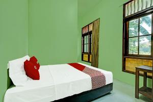 1 dormitorio con cama con almohada roja y ventana en OYO Life 91682 Homestay Sriti en Kalibanteng-kidul