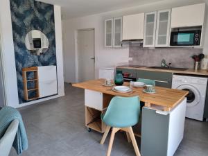 cocina con mesa de madera y silla azul en Appartement Herriko de 1 à 2 adultes et 1 enfant en Briscous