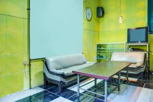 een kamer met 2 stoelen, een tafel en een tv bij OYO Life 91205 Rindang Guesthouse Syariah in Karawang
