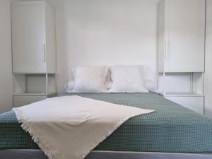 Una cama con una manta blanca encima. en Appartement Herriko de 1 à 2 adultes et 1 enfant en Briscous