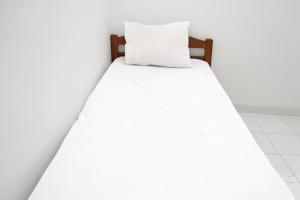 a white bed with a white pillow on it at OYO Life 92925 Kost Bu Mala 2 Syariah in Pasuruan