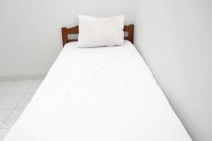 a bed with white sheets and a pillow at OYO Life 92925 Kost Bu Mala 2 Syariah in Pasuruan