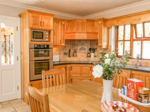 uma cozinha com armários de madeira e uma mesa com um vaso de flores em Hazelwood em Leap