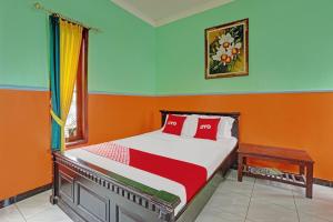 a bedroom with a bed with orange and blue walls at OYO Life 90321 Ken Ken Villa in Batu