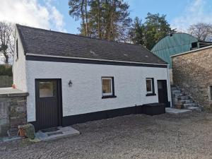 a white house with a black door and a building at The Calf House in Borrisoleigh