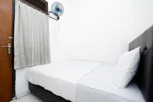 una camera da letto con un letto bianco e un riflettore sopra di OYO Life 1942 Asia Residence Syariah a Semarang