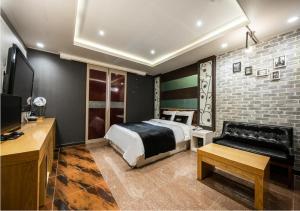 a bedroom with a bed and a couch and a tv at Hotel Kobos in Ulsan