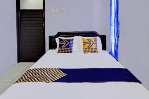 a bed with blue and yellow pillows on it at OYO Life 92353 Purnama Syariah Guest House in Blitar