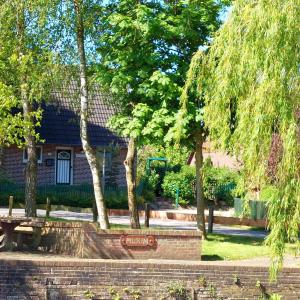 a park with a bench and trees in front of a building at Haus Dat lüttje Huus in Krummhörn +12 photos