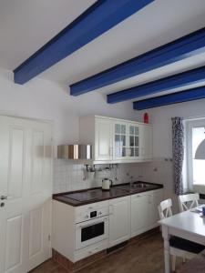 a kitchen with white cabinets and a blue ceiling at Haus Dat lüttje Huus in Krummhörn