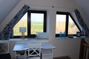 a kitchen with two windows and a table with a chair at Haus Dat lüttje Huus in Krummhörn