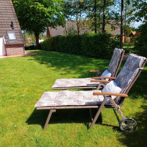 two chairs sitting in the grass in a yard at Haus Dat lüttje Huus in Krummhörn