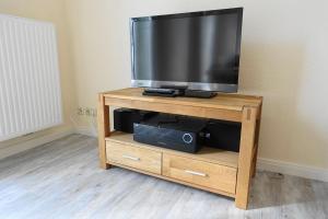 a flat screen tv on a wooden stand at Wohnung Geelina EG in Krummhörn