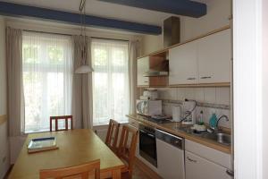 a kitchen with a wooden table and a kitchen with white cabinets at Wohnung Geelina EG in Krummhörn