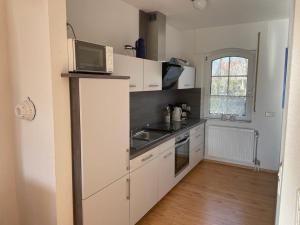 a kitchen with white cabinets and a microwave on a counter at Haus Uns Moi Hus in Krummhörn