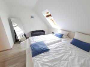 a bedroom with a white bed with blue pillows on it at Haus Uns Moi Hus in Krummhörn