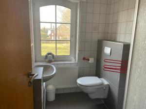 a bathroom with a toilet and a sink and a window at Haus Uns Moi Hus in Krummhörn +24 photos