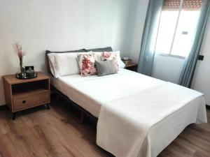 um quarto com uma cama com uma mesa de cabeceira e uma janela em Cosy flat a few min to Barcelona emblematic sites em Cornellà de Llobregat