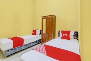 Cette chambre comprend 2 lits avec des draps rouges et blancs. dans l'établissement OYO Life 92542 Griya Sakinah Syariah, à Grobogan