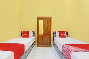 2 łóżka w pokoju z czerwonymi poduszkami w obiekcie OYO Life 92542 Griya Sakinah Syariah w mieście Grobogan