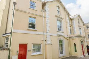 a yellow house with a red door on a street at Apartment 11 Astor House in Torquay