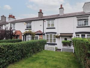 a house with a white fence and a yard at Bluebell Cottage in Ormskirk