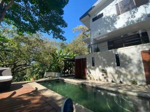 a swimming pool in front of a house at Loft Mágico en Nativa Resort in Tarcoles