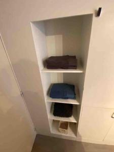 a closet with white shelves in a white wall at Appartement au calme in Hem