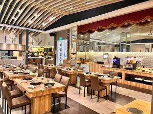 un restaurante con mesas y sillas de madera y una cocina en Tsun Huang Hotel, en Chiayi