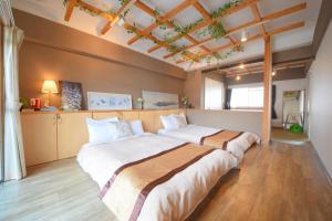 two beds in a large room with wooden floors at Comfy Stay TDS in Nara