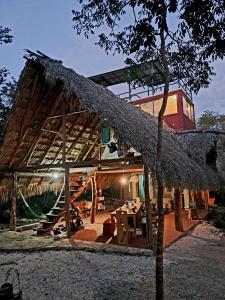 a house with a thatched roof with a table in front at Rancho Aak in Yaxché