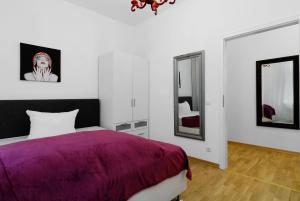 um quarto com uma cama roxa e dois espelhos em Grand Central City Apartments Mitte Rosenthaler Platz em Berlim
