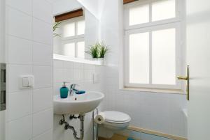 uma casa de banho branca com um lavatório e um WC em Grand Central City Apartments Mitte Rosenthaler Platz em Berlim