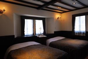 a bedroom with two beds and two windows at Petit Hotel & Restaurant Old Age in Hokuto