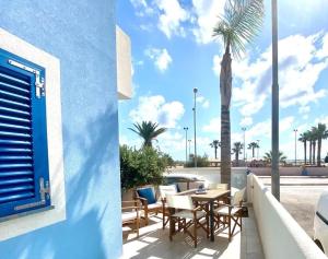 a patio with a table and chairs and a palm tree at Zefiro&Levante2 Residence Luce del Mare in San Vito lo Capo