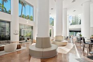 - un hall avec des tables et des chaises blanches et des palmiers dans l'établissement Crowne Plaza Surfers Paradise, an IHG Hotel, à Gold Coast