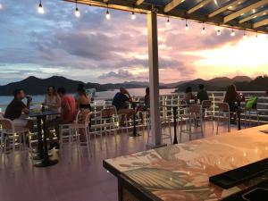 a group of people sitting at tables in a restaurant at Sunburn Suites and Rooftop Bar in Coron