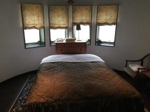 Bett in einem Zimmer mit Fenstern und Tagesdecke in der Unterkunft Petit Hotel & Restaurant Old Age in Hokuto