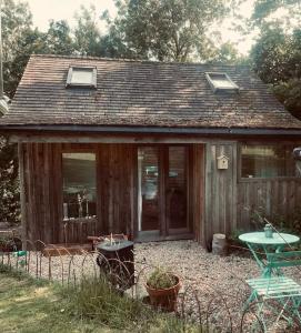 Casa de madera pequeña con mesa y ventanas en The Cabin at Shambala- now with sauna available to book! en Whitby