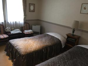 ein Hotelzimmer mit 2 Betten und einem Fenster in der Unterkunft Petit Hotel & Restaurant Old Age in Hokuto