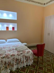 um quarto com uma cama e uma cadeira vermelha em Casa Vacanze Miriam em Randazzo