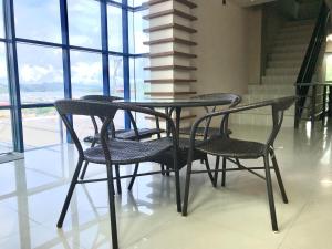 une table avec trois chaises et une table avec des fenêtres dans l'établissement Sunburn Suites and Rooftop Bar, à Coron