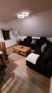 sala de estar con sofá negro y mesa en Ferienhaus Wotan, en Thale