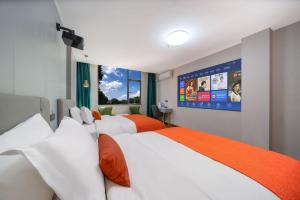 ein Hotelzimmer mit 2 Betten und einem großen Bildschirm in der Unterkunft Guangzhou Yashay International Apartment - Pazhou Convention and Exhibition Centre in Guangzhou