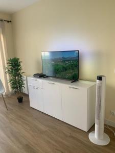 TV de pantalla plana en la parte superior de un centro de entretenimiento blanco en Studio LES ORANGERS, en Cagnes-sur-Mer