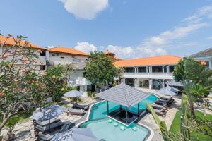 een uitzicht over een hotel met een zwembad, stoelen en parasols bij Casa Wina Kuta in Kuta