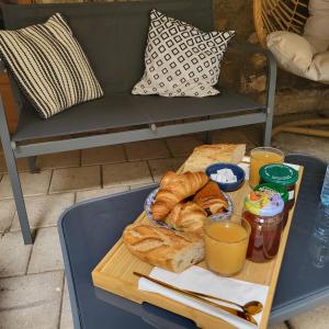 einen Tisch mit einem Tablett mit Brot und Orangensaft in der Unterkunft Chambre d'hôtes Gard in Meynes