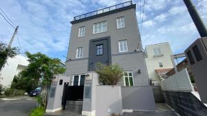 a large white building with a black door at Tabinoteitaku Kamakura Yuigahama -Homann Concept- in Kamakura
