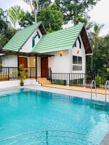 a house with a swimming pool in front of it at Regalia Wayanad in Kalpetta